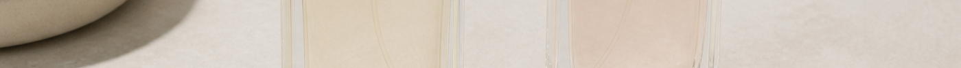 Two unbranded perfume bottles with paper test strips laid out for fragrance comparison on a light surface